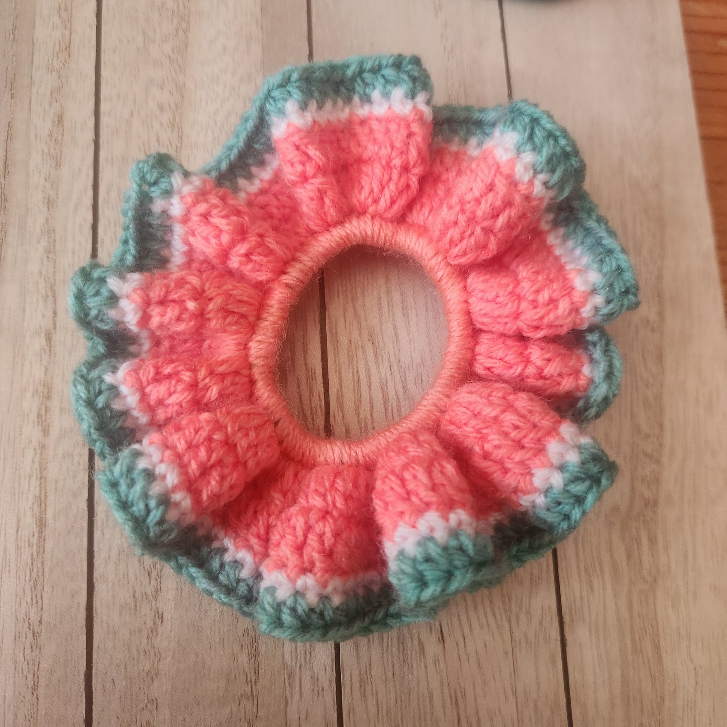 Crocheted pink and green bowl on a wooden surface