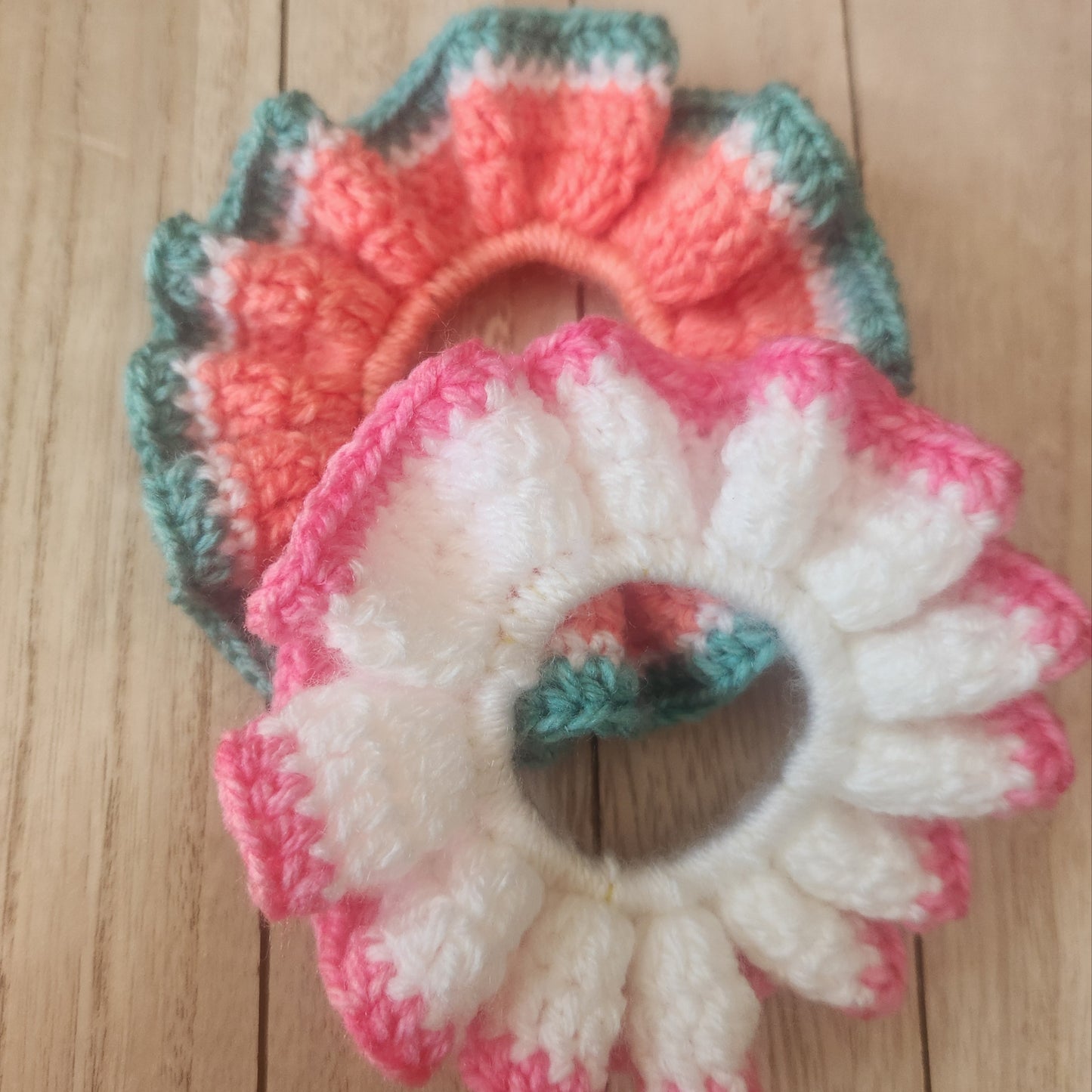 Two crocheted flower coasters on a wooden surface