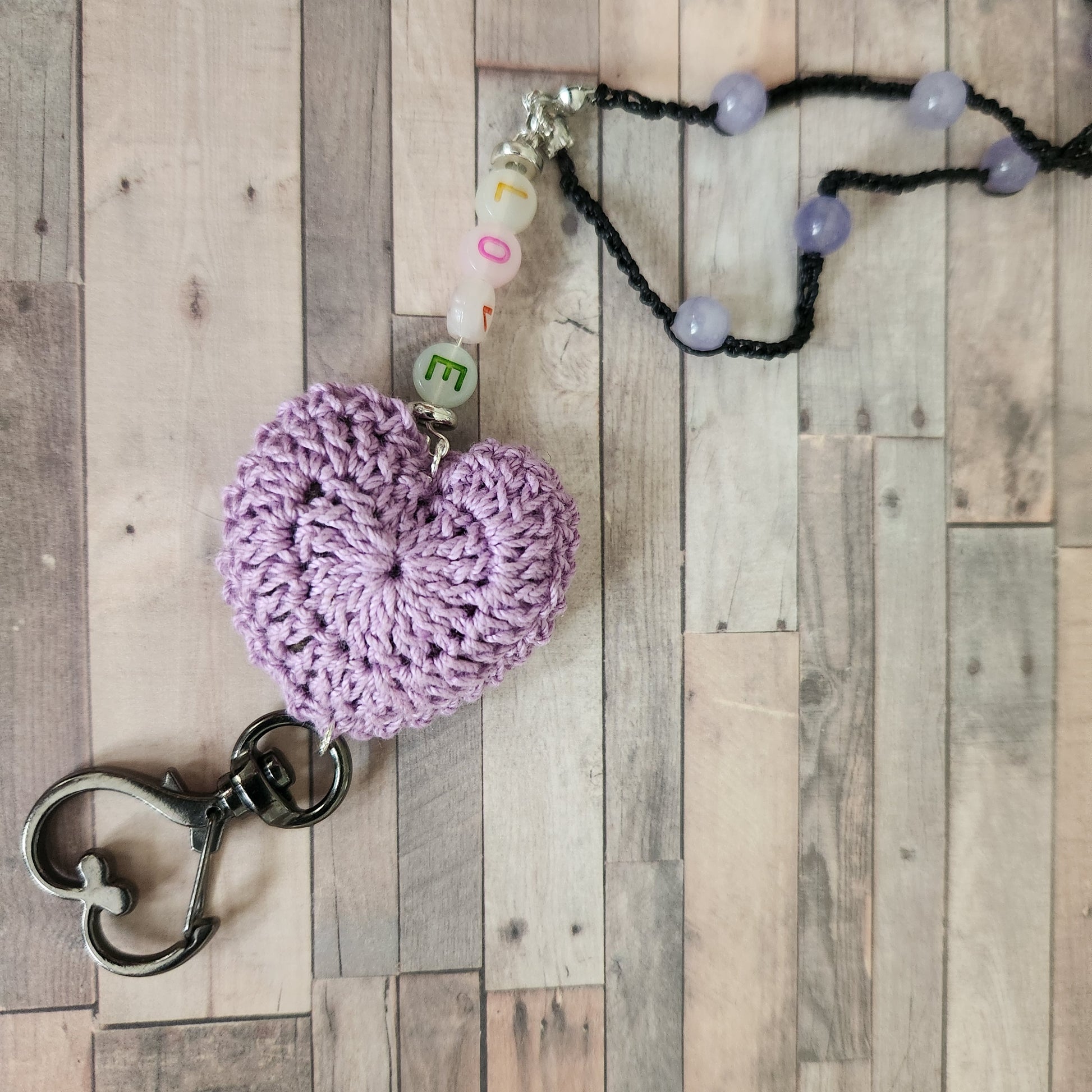 showing the making of a heart lanyard, purple dyed quartz beads with black s-lon cord and a crochet purple heart (cotton)